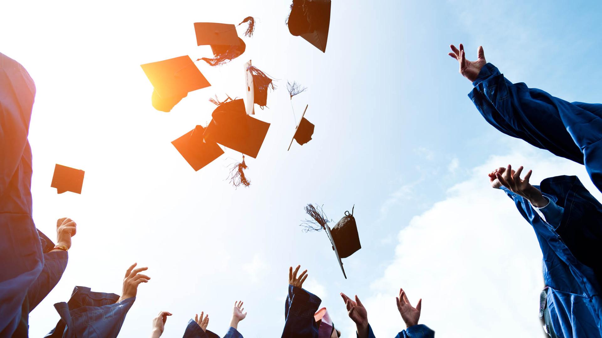 Group of graduate students throwing graduation hats to the sky